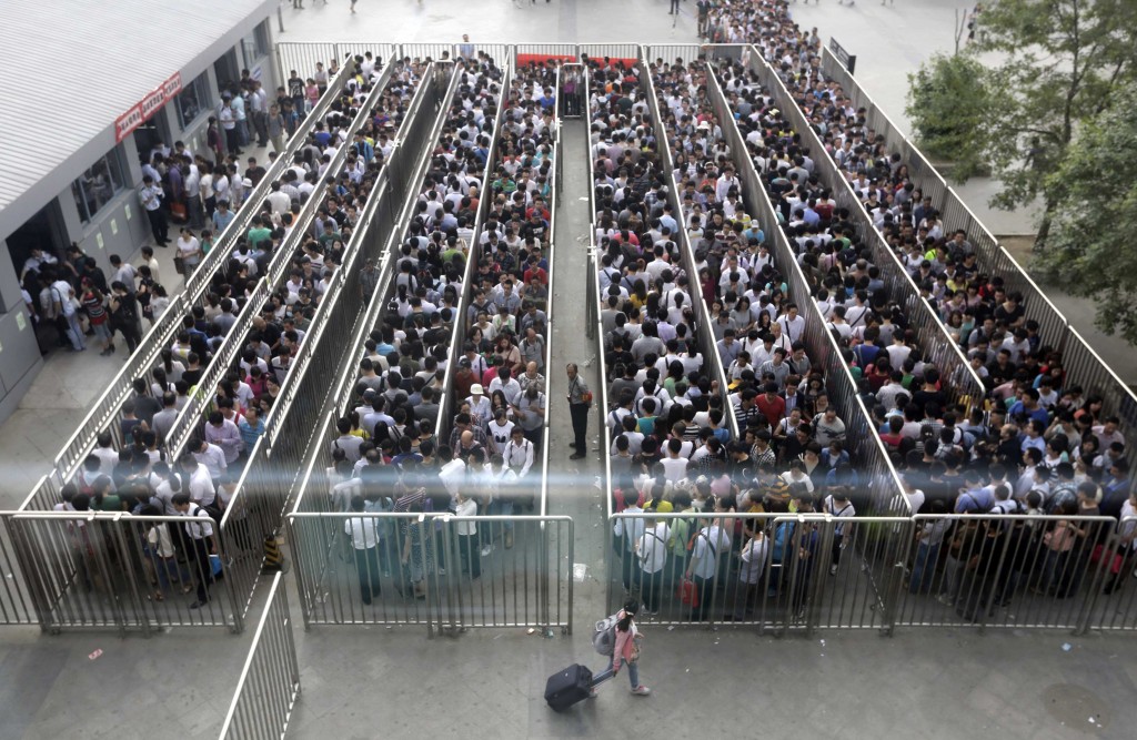 Passengers line up and wait for a security check during morning rush hour at Tiantongyuan North Station in Beijing