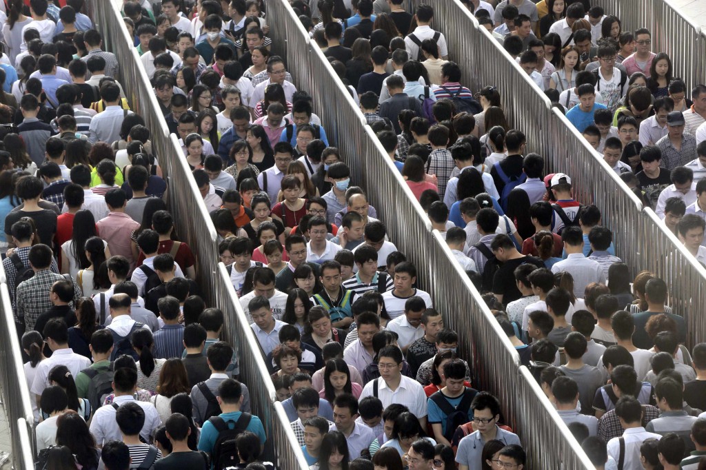 Passengers line up and wait for a security check during morning rush hour at Tiantongyuan North Station in Beijing