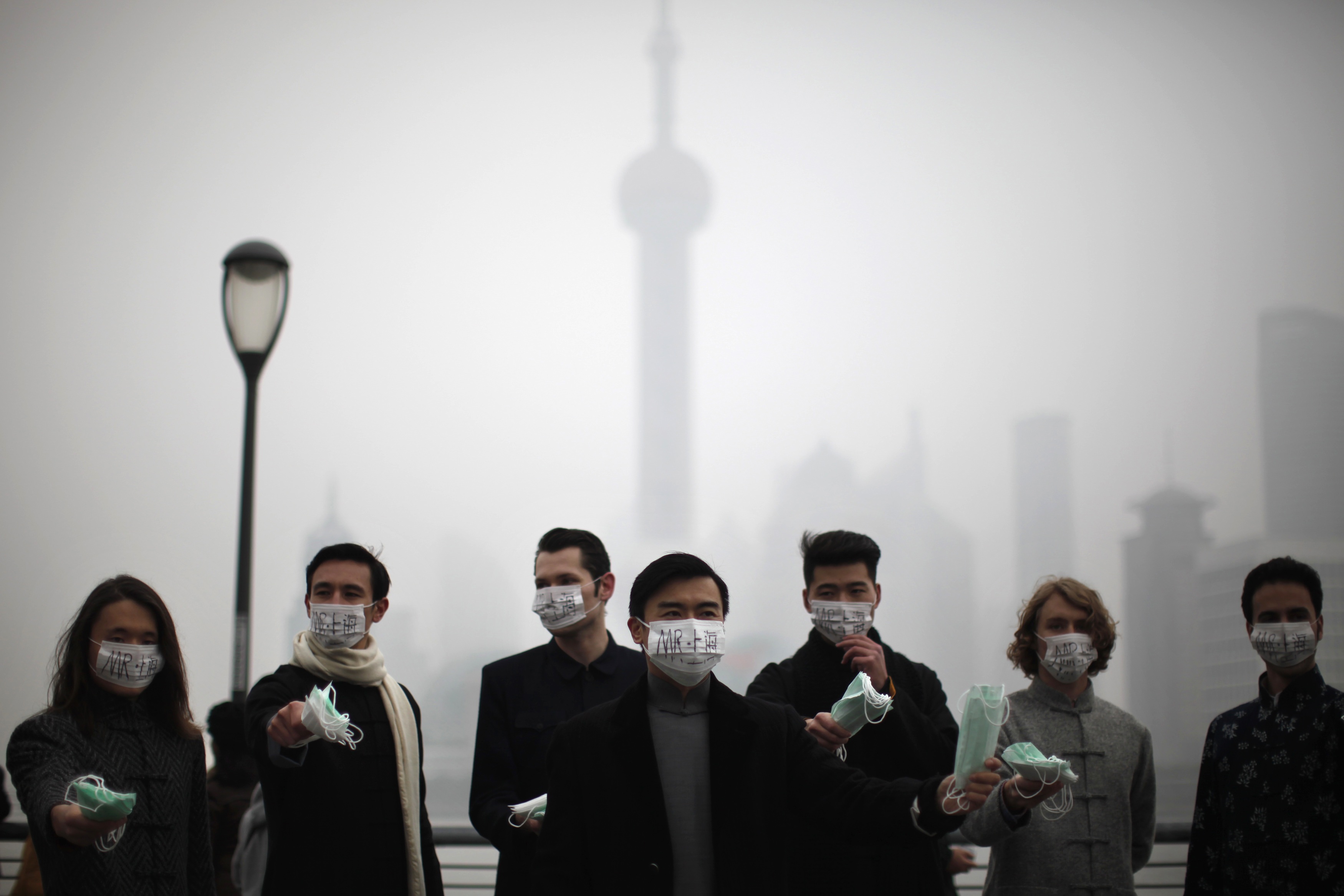 A group of expatriates stand along the Bund as they distribute face masks to pedestrians to raise awareness of air pollution in downtown Shanghai